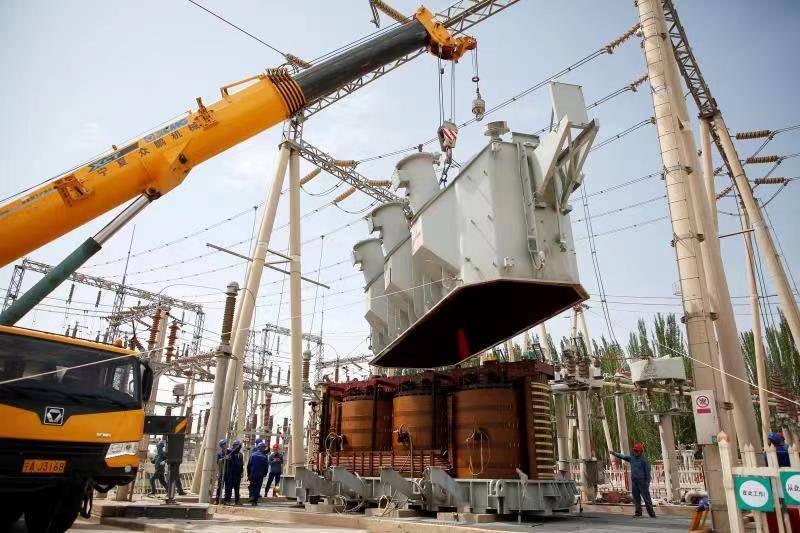 队队旗随风飘扬,伴随着重型起重机的轰鸣声,沉重的主变压器钟罩被徐徐