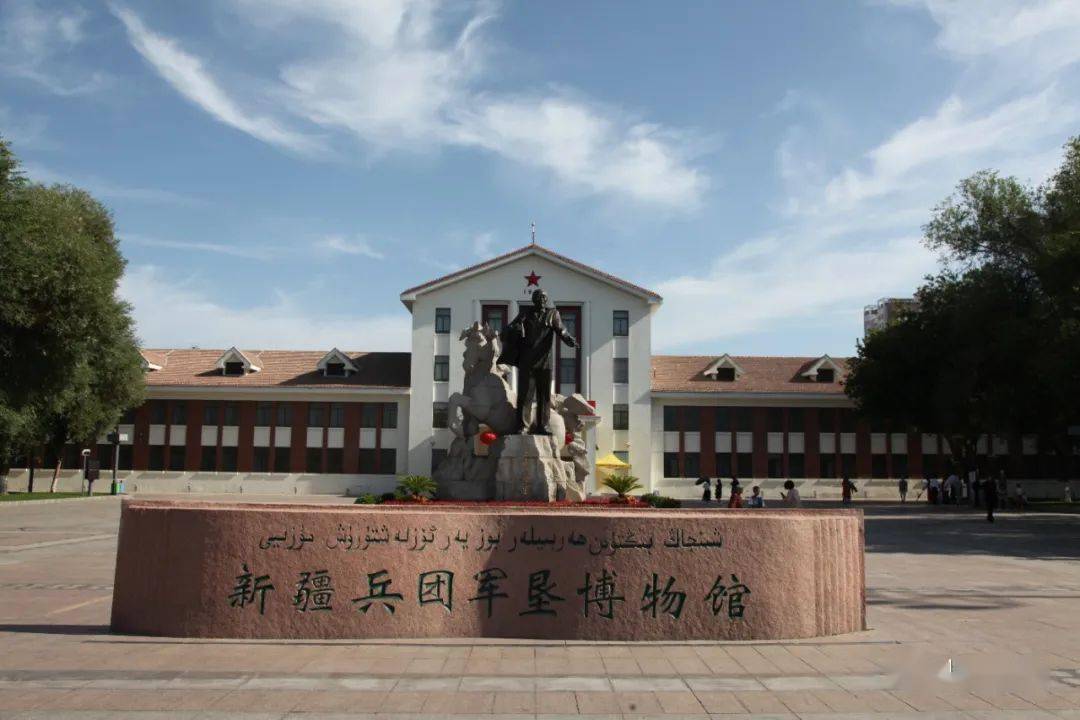 雕像的背后是军垦博物馆,正门楼的顶沿上悬挂着"弘扬兵团精神,赓续