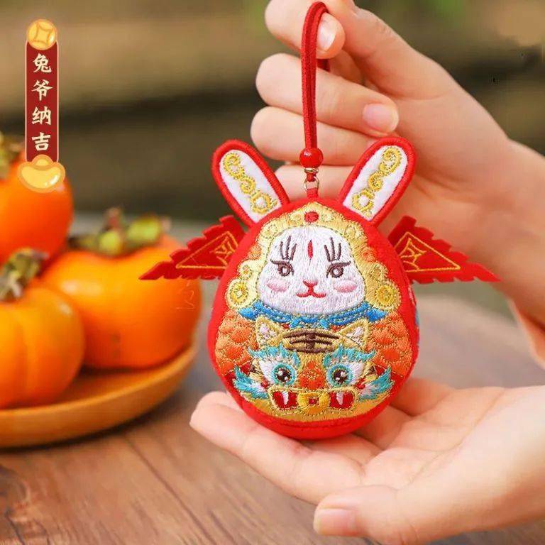 采用老北京传统兔爷儿形象,披红袍,插令旗,笑眯眯地抱着吉祥物,生动