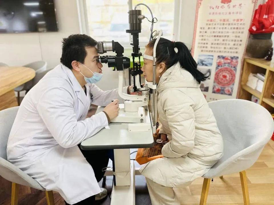 来自威海骨科医院的眼科医生仔细为居民进行白内障检查与视力测试